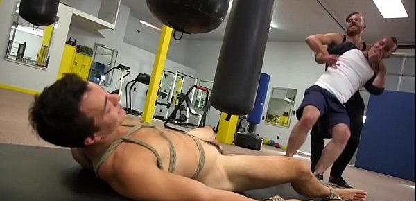  BDSM doms share restrained subs cock in gym